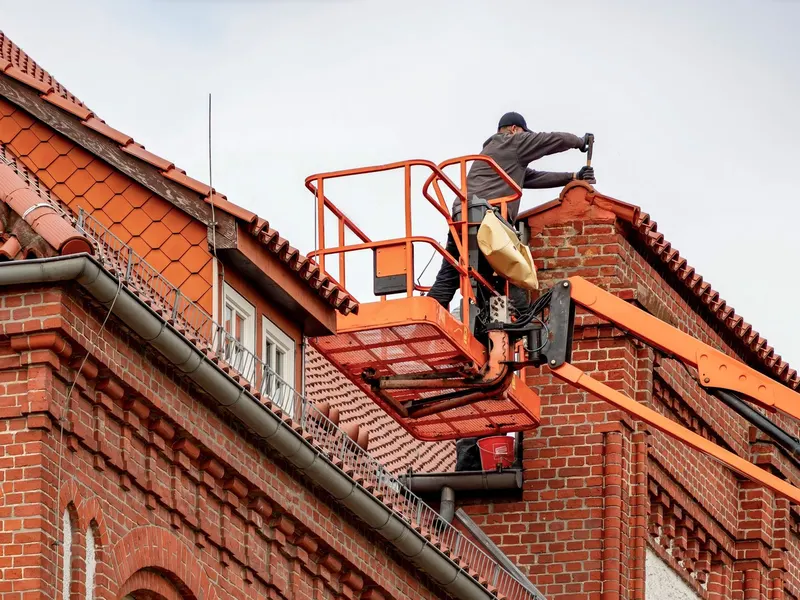 Worker cleaning gutters on a roof