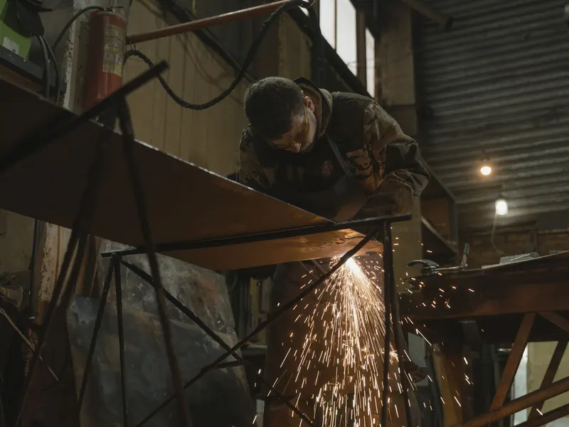 Welder fabricating metal with sparks