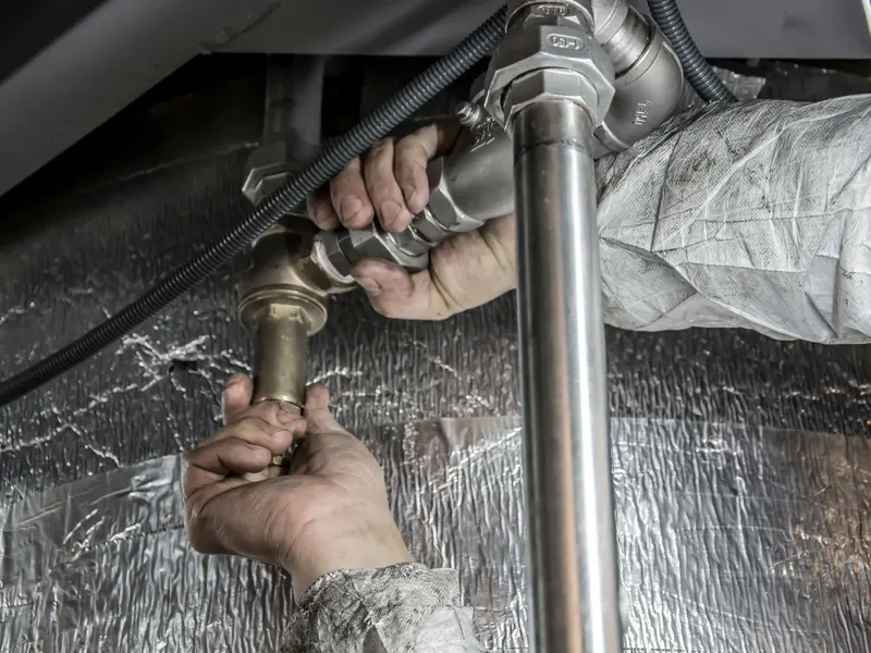 Plumber repairing pipes under a sink
