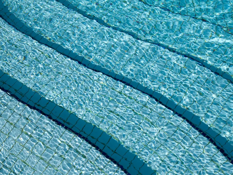 Clear swimming pool water over patterned tiles